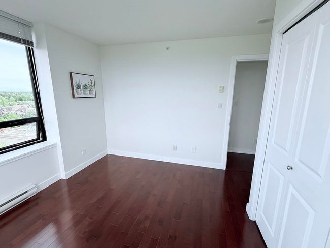 Empty room featuring dark wood-style floors and a baseboard heating unit | Image 14
