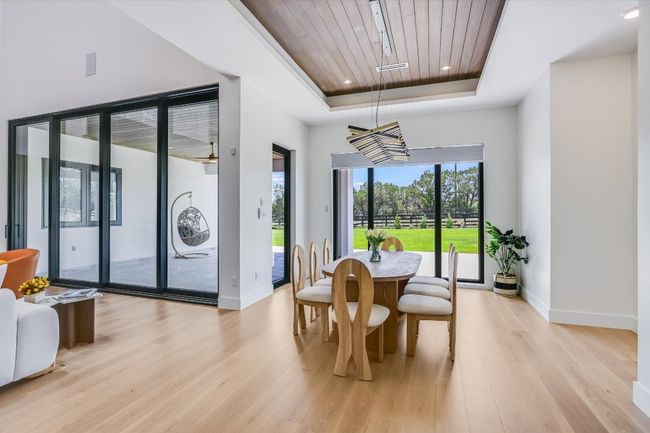 Dining room featuring a tray ceiling, wood ceiling, light wood floors, and recessed lighting as well as custom chandelier | Image 20
