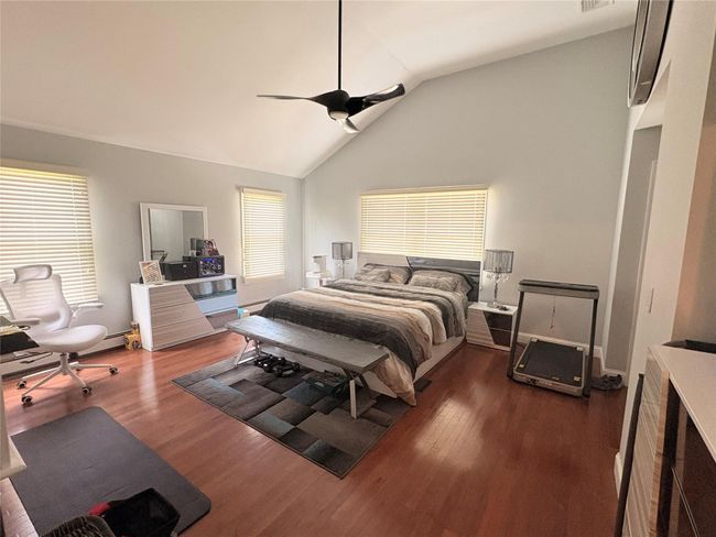 Bedroom featuring vaulted ceiling, multiple windows, wood finished floors, and a ceiling fan | Image 9