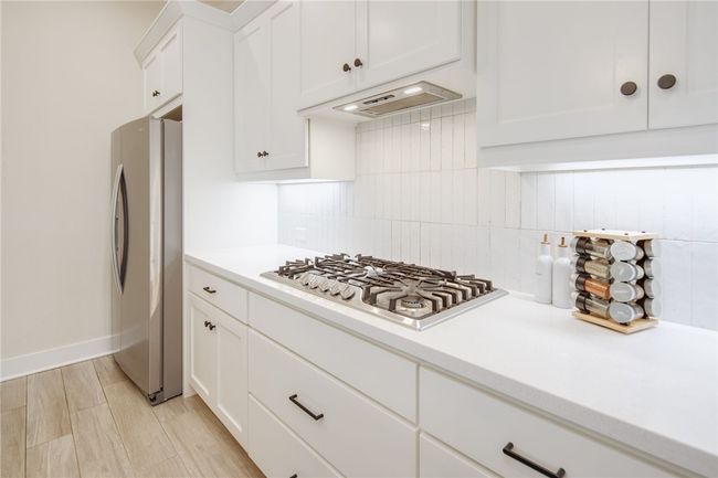 Kitchen with appliances with stainless steel finishes, tasteful backsplash, light countertops, and white cabinetry | Image 9