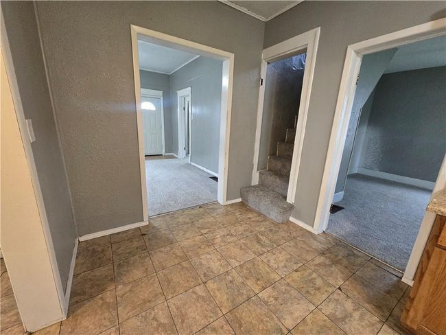 Hallway featuring carpet, crown molding, baseboards, stairway, and a textured wall | Image 9