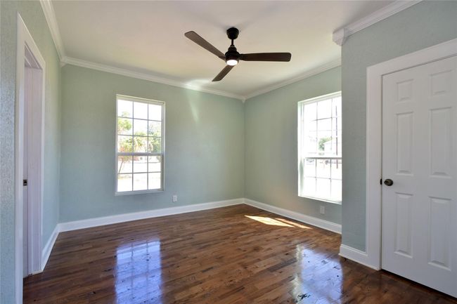 Empty room with crown molding, dark wood-style flooring, and a ceiling fan | Image 11
