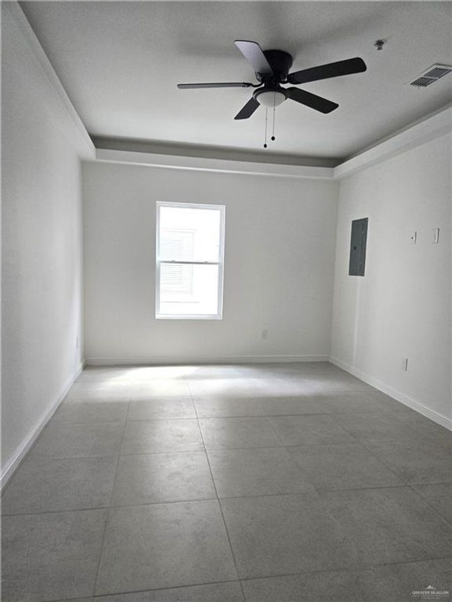 Empty room with electric panel, ceiling fan, and a pendent fire sprinkler | Image 5