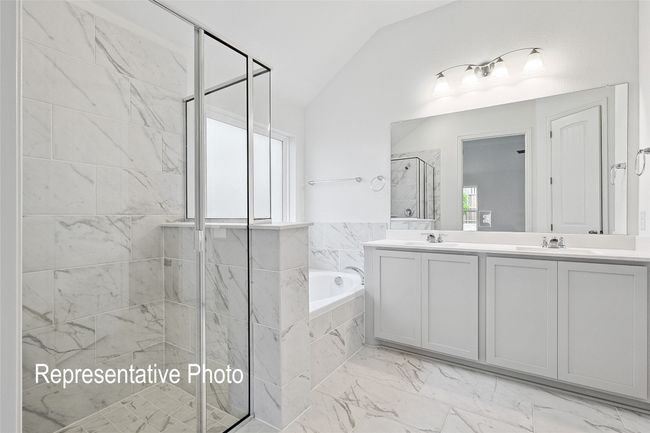 Bathroom featuring a shower stall, a garden tub, a sink, marble finish floor, and lofted ceiling | Image 10