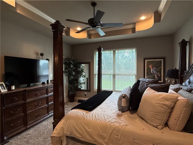 Carpeted bedroom featuring ornate columns, ornamental molding, recessed lighting, ceiling fan, and a tray ceiling | Image 11