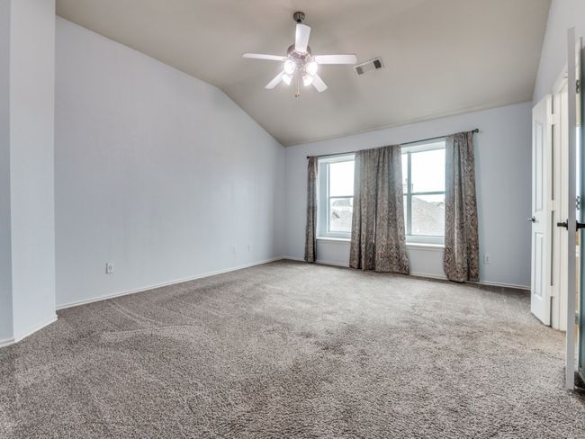 Carpeted spare room featuring ceiling fan, visible vents, vaulted ceiling, and baseboards | Image 16