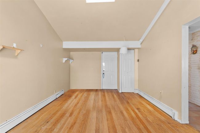 Empty room featuring a baseboard radiator and wood finished floors | Image 12