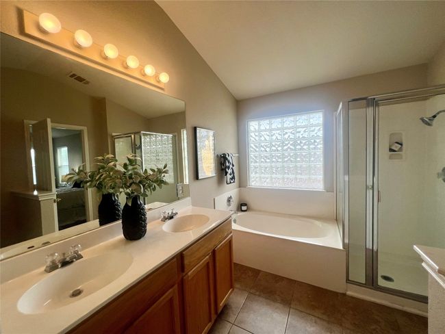 Full bathroom featuring a bath, a shower stall, lofted ceiling, double vanity, and tile patterned floors | Image 22