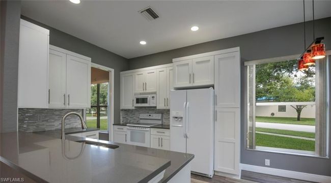 Kitchen with hanging light fixtures, sink, white cabinets, and white appliances | Image 4