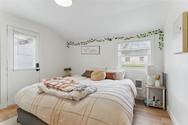 Bedroom with light wood-style floors, lofted ceiling, and visible vents | Image 32