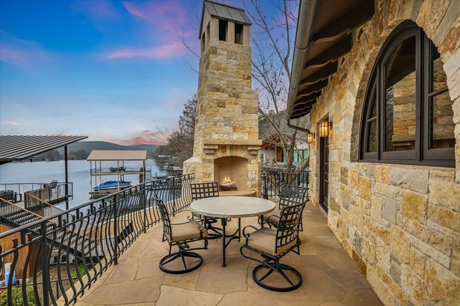 View of patio featuring an outdoor stone fireplace | Image 38