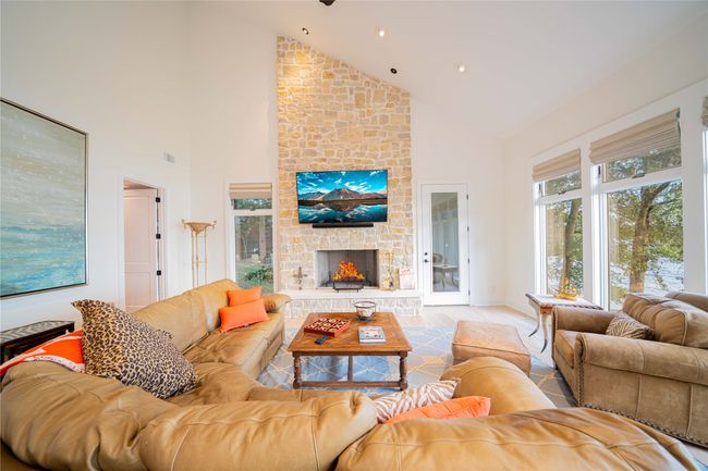 Living area with high vaulted ceiling, a stone fireplace, wood finished floors, and recessed lighting | Image 14