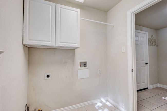 Laundry area featuring light tile patterned floors, hookup for an electric dryer, hookup for a washing machine, and cabinets | Image 28