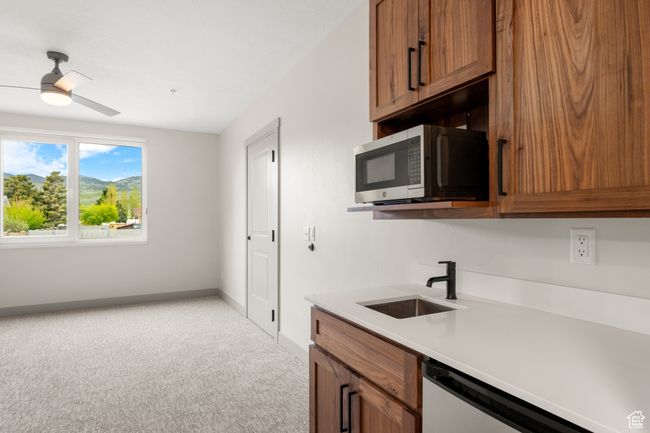 Kitchen featuring stainless steel microwave, a sink, light carpet, and brown cabinets | Image 18