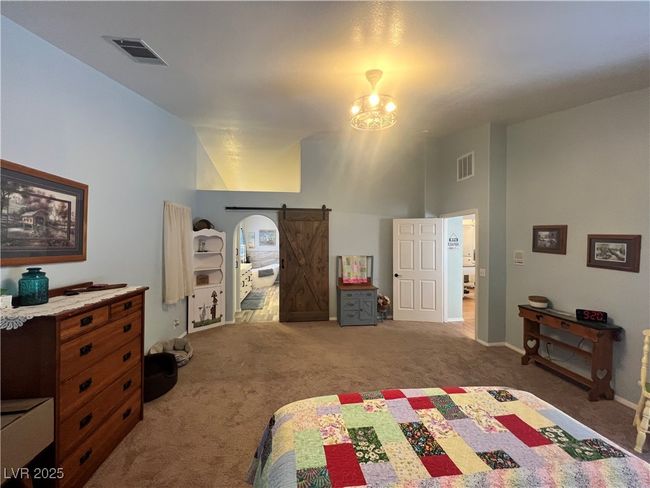 Carpeted bedroom featuring vaulted ceiling and a barn door | Image 29