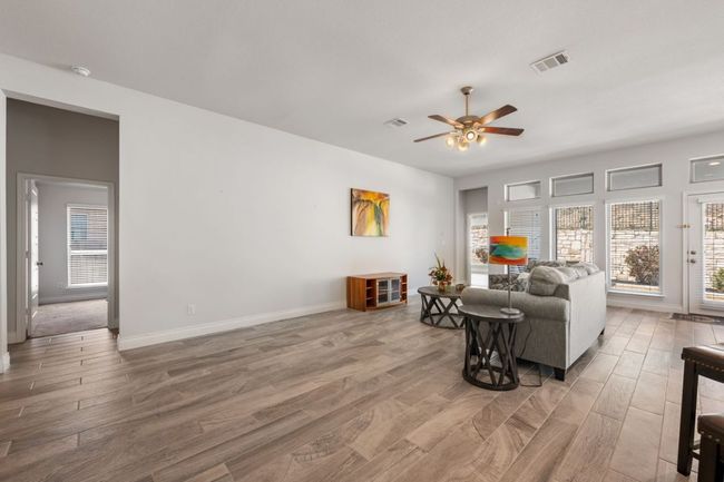 Living area with baseboards, wood finished floors, visible vents, and ceiling fan | Image 10