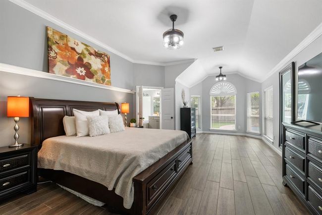 Retire each day in a primary suite that promotes relaxation. The primary bedroom is accented with a bay window seating/office are, two ceiling fans, and crown molding. | Image 23