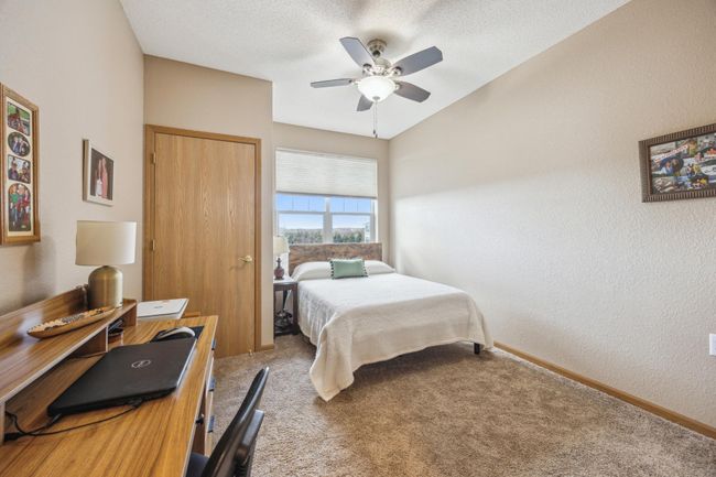Second bedroom featuring a ceiling fan with lights, soft shade on the double-wide window, and ample space for a guest bed and a desk. A large closet adds extra storage for your convenience. | Image 18