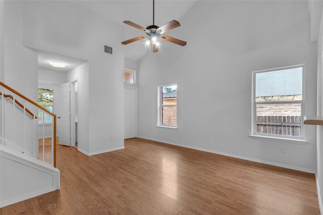 Empty room featuring high vaulted ceiling, stairway, a ceiling fan, and wood finished floors | Image 10