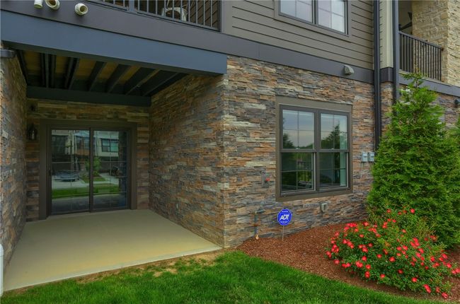 This private lower-level patio offers a peaceful retreat with stone-accented walls, a covered seating area, and easy walk-out access—perfect for relaxing or entertaining outdoors. | Image 48