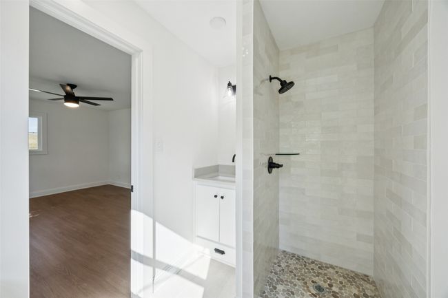 Bathroom featuring a tile shower, ceiling fan, vanity, and wood finished floors | Image 14