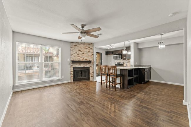 Living room featuring a ceiling fan, dark wood-type flooring, and a stone fireplace | Image 7