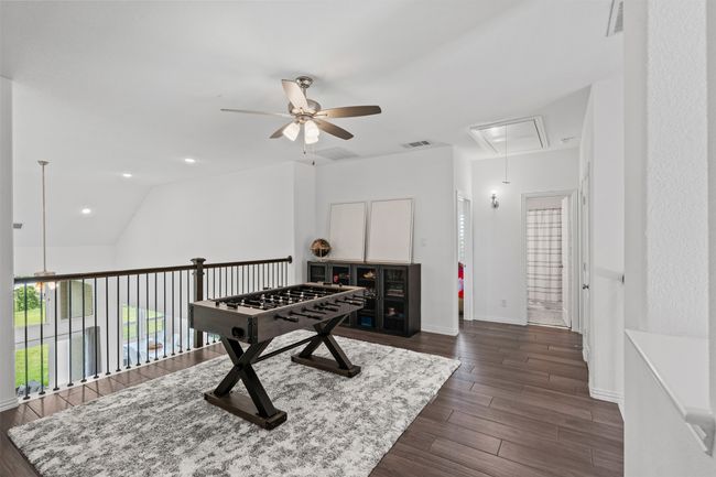 Recreation room with attic access, a ceiling fan, dark wood-style flooring, baseboards, and lofted ceiling | Image 25