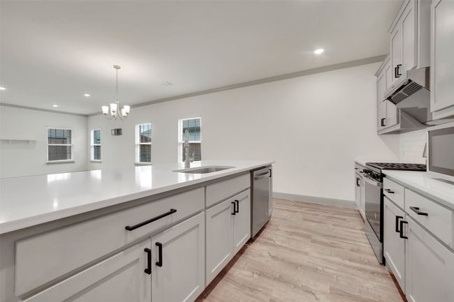 Kitchen featuring a notable chandelier, light countertops, range with gas cooktop, dishwasher, and hanging light fixtures | Image 9