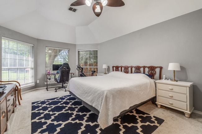 Bedroom with light carpet, baseboards, vaulted ceiling, ceiling fan, and an office area | Image 25