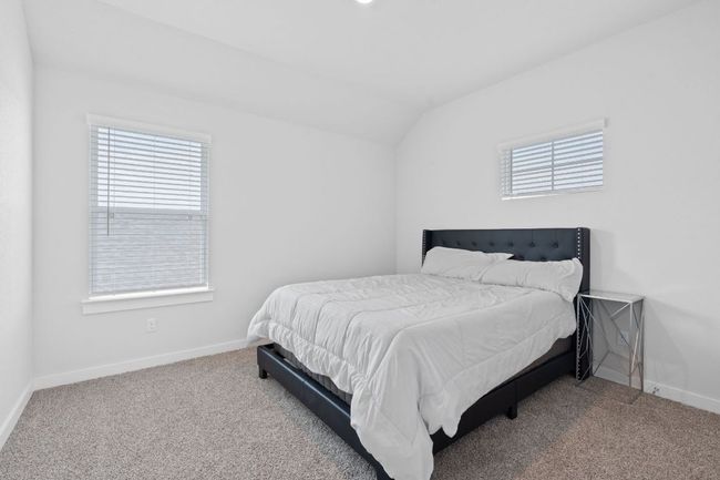 Carpeted bedroom with vaulted ceiling, baseboards, and multiple windows | Image 19