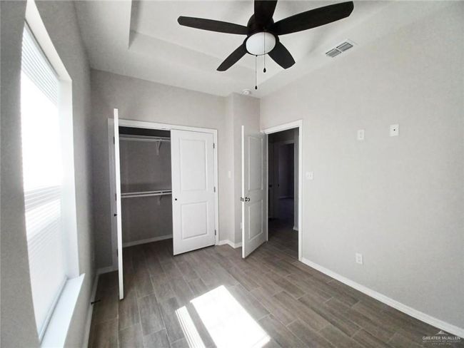 Unfurnished bedroom featuring a closet, baseboards, wood finish floors, and a tray ceiling | Image 8