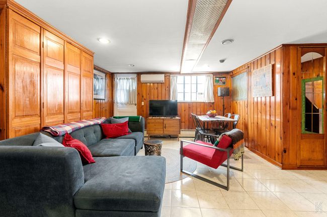 Living area featuring a wall mounted air conditioner, wooden walls, light tile patterned floors, and baseboard heating | Image 15