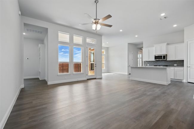 Unfurnished living room featuring dark wood finished floors, visible vents, baseboards, and ceiling fan | Image 14