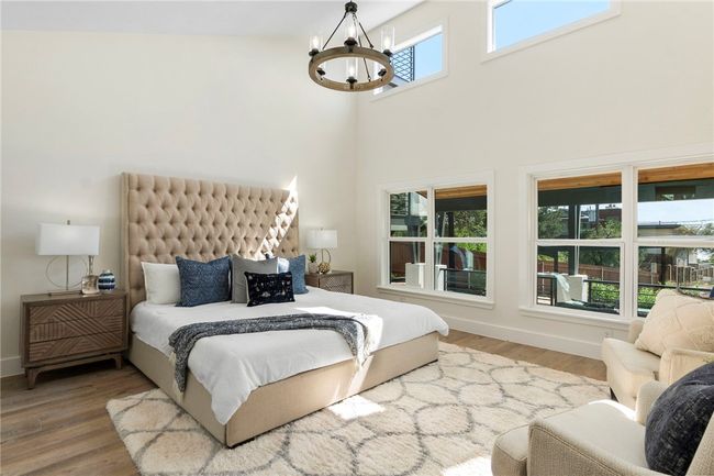 The primary bedroom is a haven of relaxation with a lofty vaulted ceiling, a stunning chandelier, and large windows that invite the sunlight. | Image 17