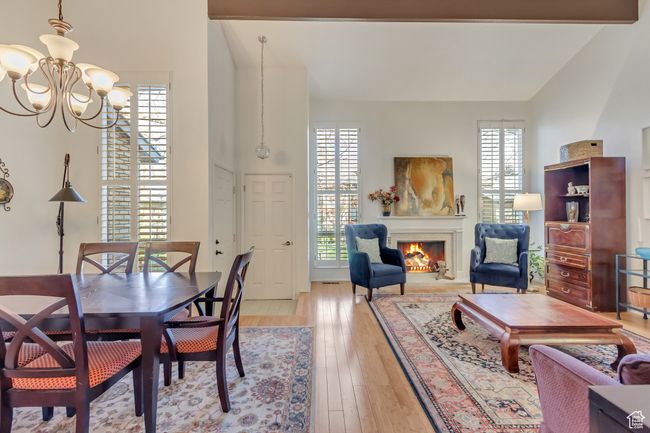 Dining space with a wealth of natural light, a notable chandelier, a lit fireplace, and light wood finished floors | Image 10