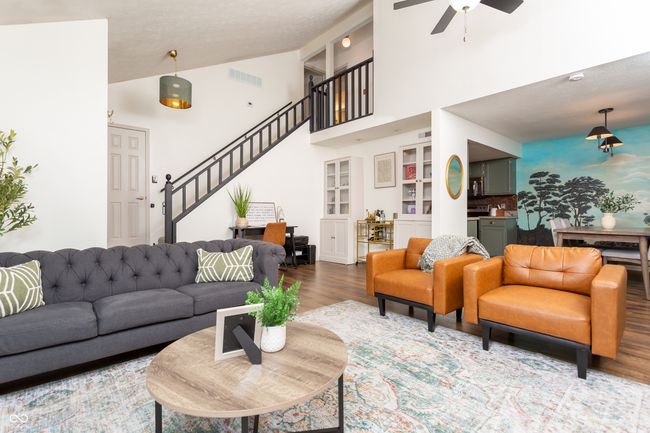 living area featuring wood finished floors, high vaulted ceiling, stairway, ceiling fan, and built in shelves | Image 9