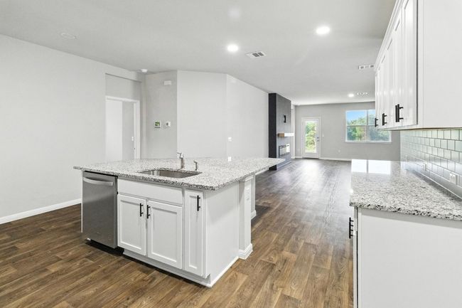 Kitchen featuring stainless steel dishwasher, dark wood-style flooring, white cabinetry, a center island with sink, and recessed lighting | Image 4