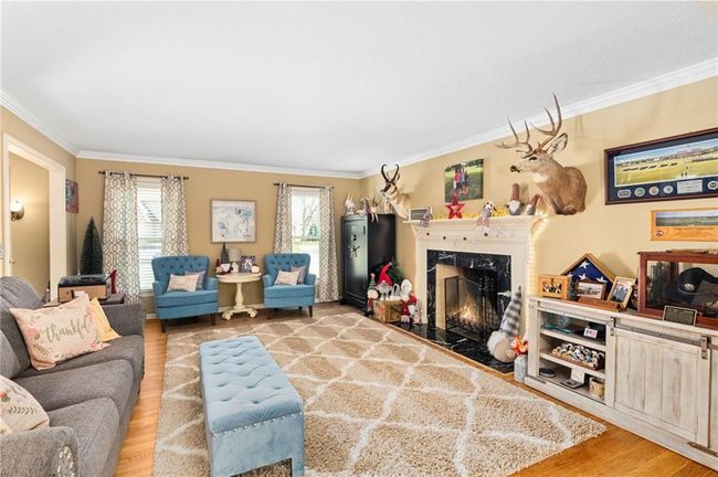 Living room featuring crown molding, a fireplace, and light hardwood / wood-style flooring | Image 8