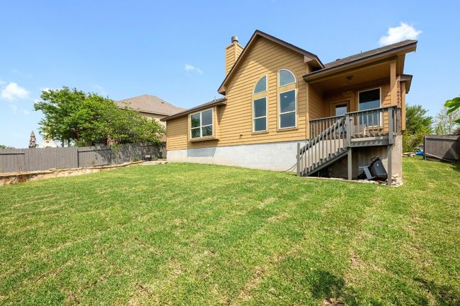 The back of the home showcases charming architectural details, a cozy elevated deck, and large windows that flood the interior with natural light. A perfect space for enjoying sunsets and outdoor gatherings. | Image 28