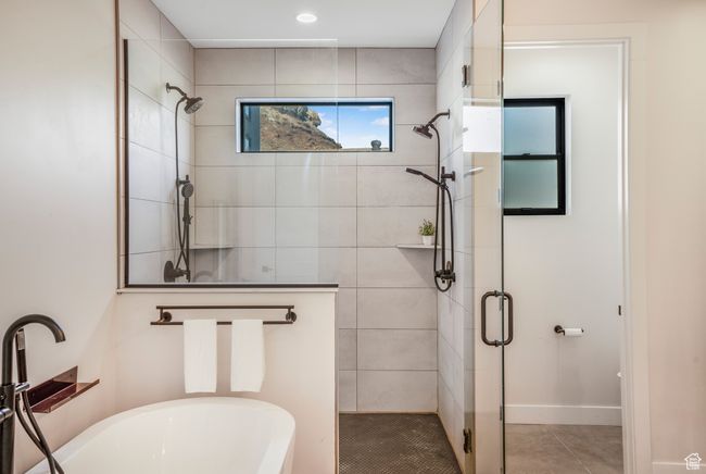 Bathroom with a stall shower, baseboards, tile patterned flooring, and a freestanding bath | Image 28