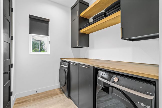 Laundry area featuring independent washer and dryer, light wood-type flooring, cabinet space, and baseboards | Image 29