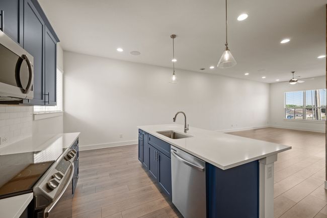 Kitchen featuring blue cabinets, light wood-style flooring, a sink, a ceiling fan, and appliances with stainless steel finishes | Image 20