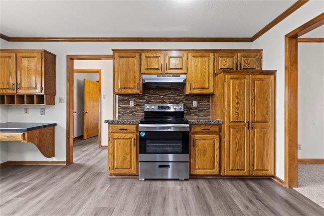 Kitchen featuring stainless steel electric stove, backsplash, crown molding, and light hardwood / wood-style floors | Image 17