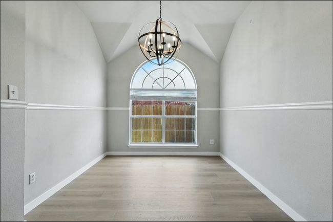 Unfurnished dining area featuring a chandelier, wood finished floors, and lofted ceiling | Image 17