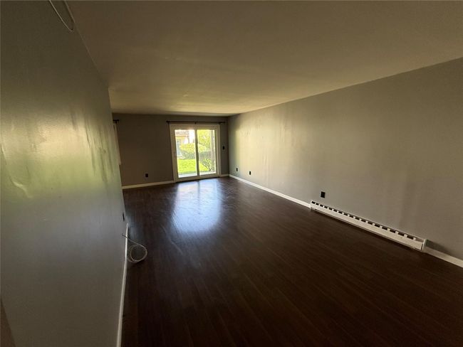 Spare room featuring baseboards, baseboard heating, and dark wood-type flooring | Image 9