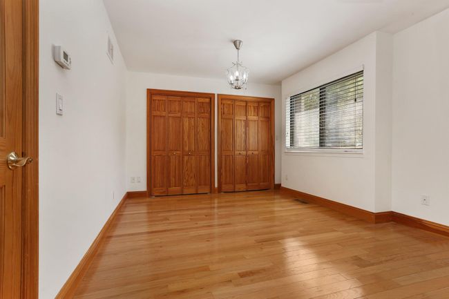 Unfurnished bedroom featuring a chandelier, light wood-type flooring, baseboards, and multiple closets | Image 27