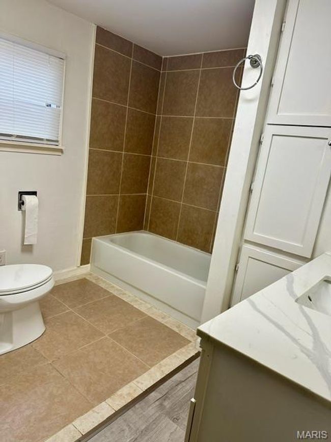 Full bathroom with tile patterned flooring, vanity, toilet, and tiled shower / bath combo | Image 28