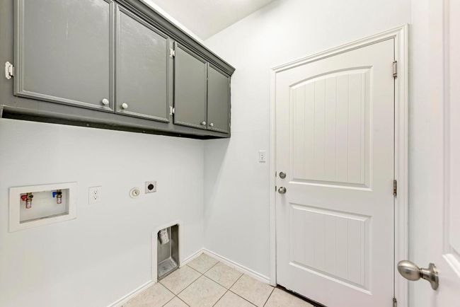 Laundry room with cabinet space, electric dryer hookup, light tile patterned floors, hookup for a washing machine, and baseboards | Image 32