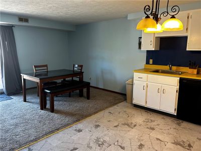 Kitchen with dishwasher, light colored carpet, decorative and light fixtures. | Image 3