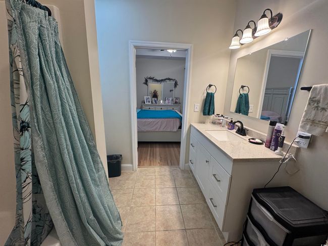 Ensuite bathroom with tile patterned flooring, vanity, curtained shower, and baseboards | Image 15